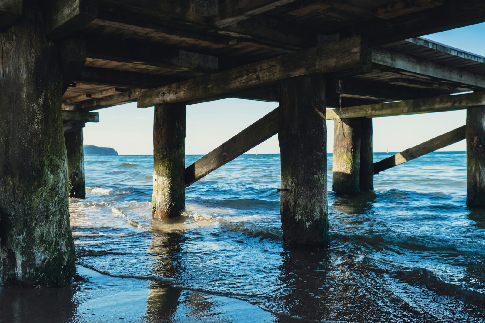 Storm sea waves under wooden pier in dramatic background wallpaper design. Seascape with running